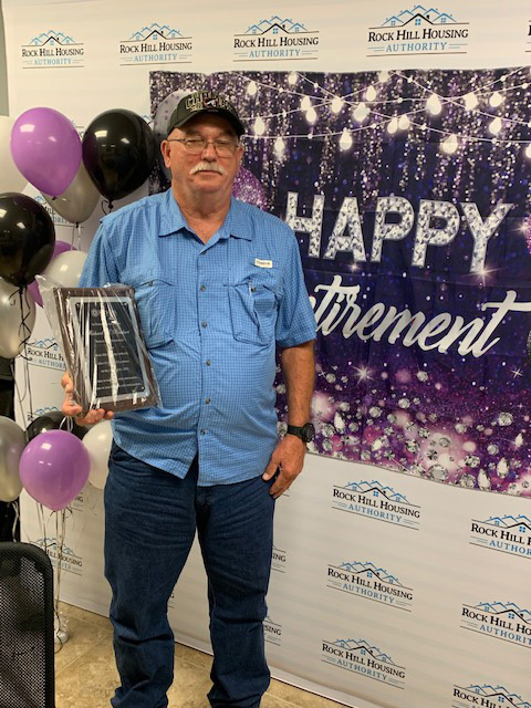 Rick Rinehart standing in front of a sign that reads Happy Retirement.