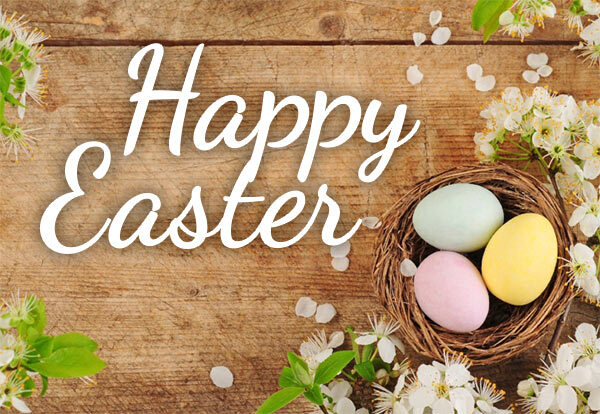 Happy Easter! Three colorful eggs sit in a nest on a wooden table. 