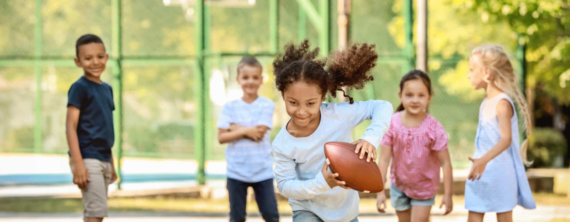 Kids outside and playing with a football..