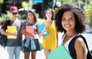 A girl smiling in the foreground, with three other students smiling in the background.