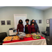 Three women posing in front of food