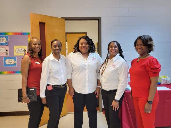 2 ladies in red outfits and 3 ladies in white shirts smiling 