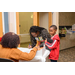 A woman leans over a table and signs in herself and her young son. 