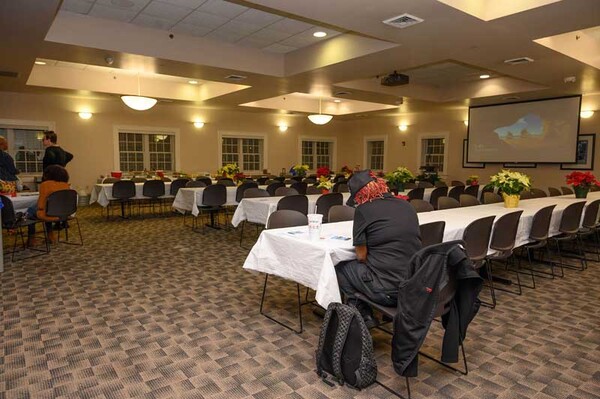 Four long tables are in the middle of the room; Christmas center pieces line the centers of the tables. 