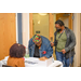 Two women are at the sign-in table and one of them is leaned over to sign her name on the sign-in sheet. 