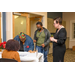 A woman talks to the women at the sign-in table and while of them is leaned over to sign her name on the sign-in sheet. 