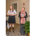 A woman in a long scarf stands next to a woman in cowboy boots and addresses the room. 