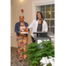 Two women stand behind the podium; one looks down into a box while the other looks away and reaches into the box. 