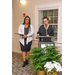 Two women stand behind the podium; one is smiling while the other speaks. 