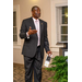 A tall gentleman in a suit looks to the right as he addresses the room.