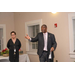 A tall gentleman in a suit stands next to a woman in black-rimmed glasses while he addresses the room.