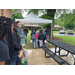 Families standing near a tent and park bench.