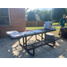 Pizza boxes are on an outdoor picnic table with a man in a number 7 football jersey is staning next to the talbe. 