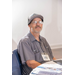  A man sitting at a table wearing a baseball cap.  
