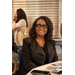  Woman in glasses is smiling while seated at a table.  