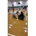  A young boy helping another young boy tie his shoes. 